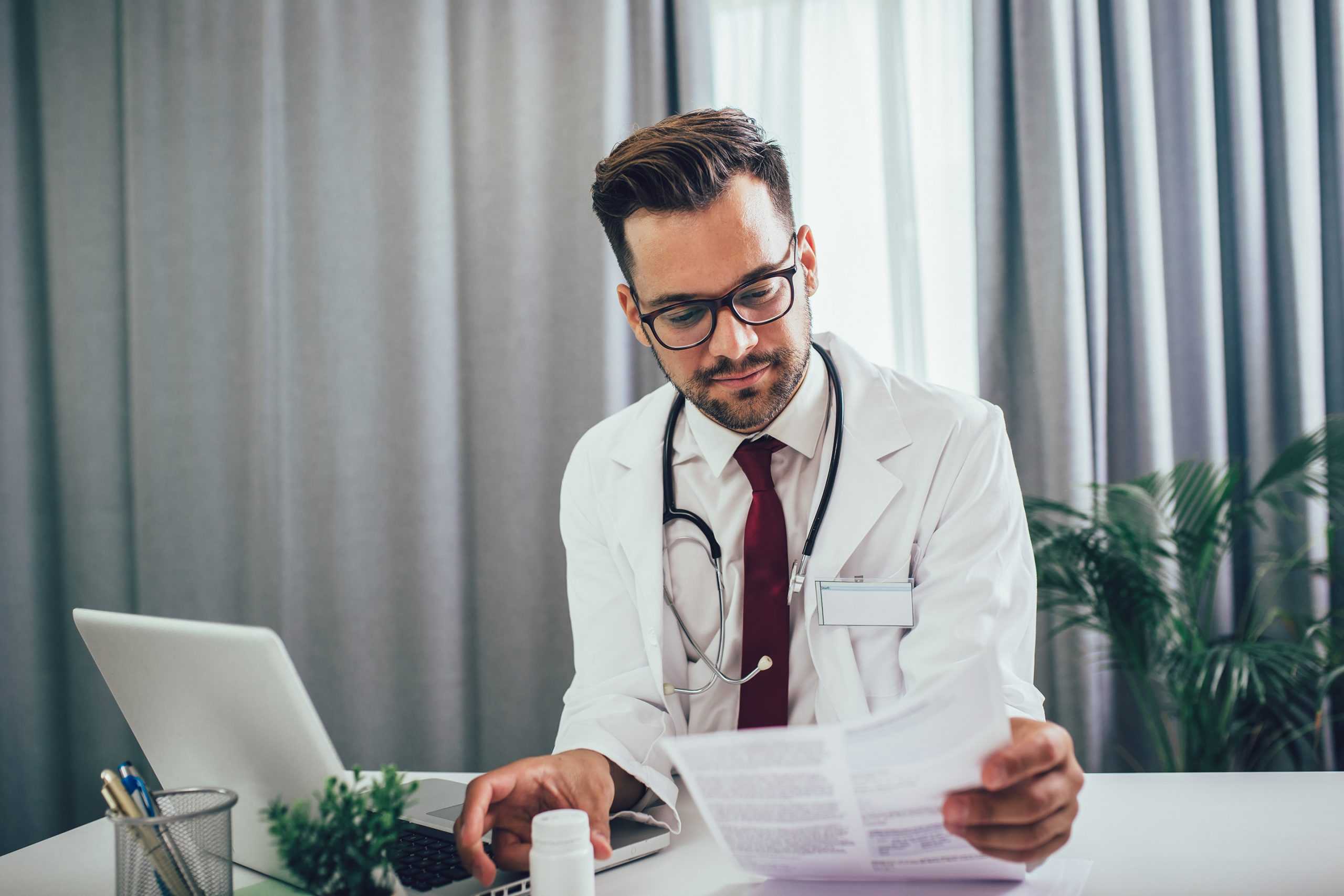 a male physician looking at paperwork for a corvel virtual care appointment