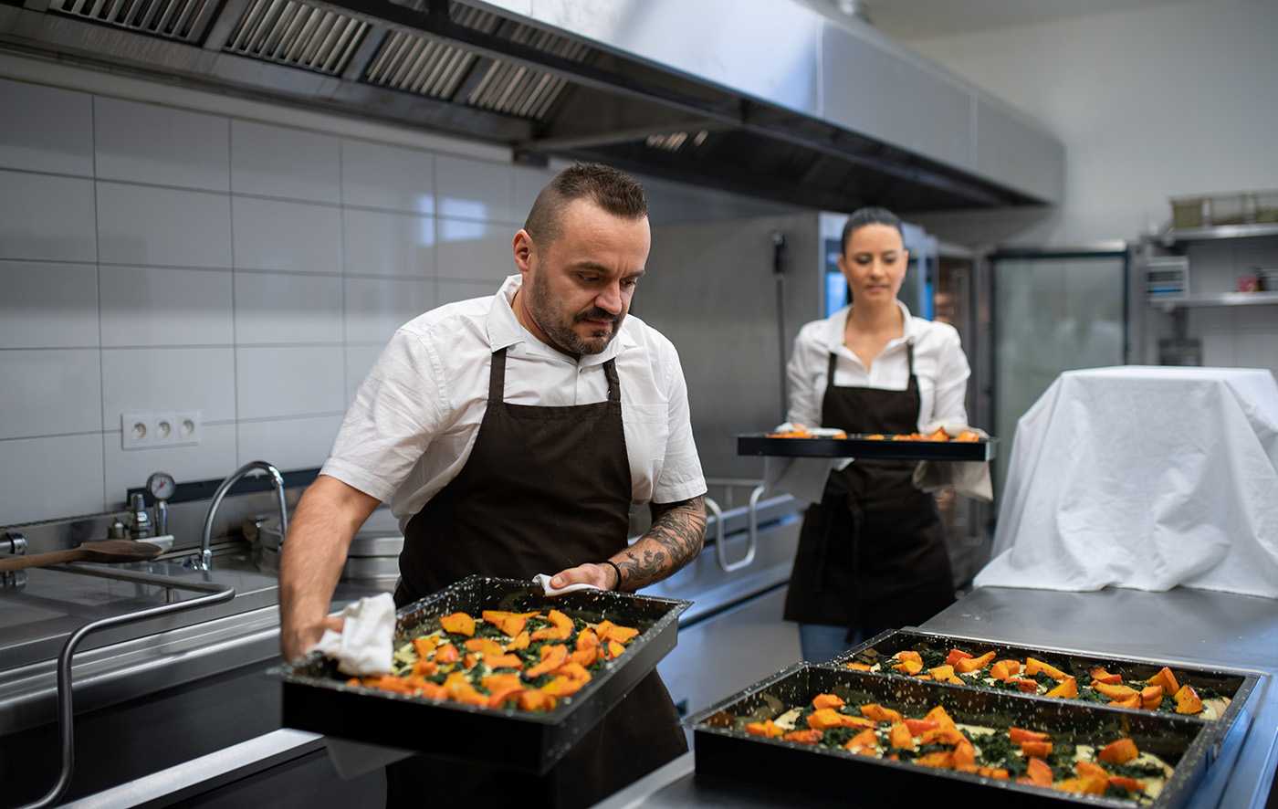 a male cook and female cook preparing food in a kitchen