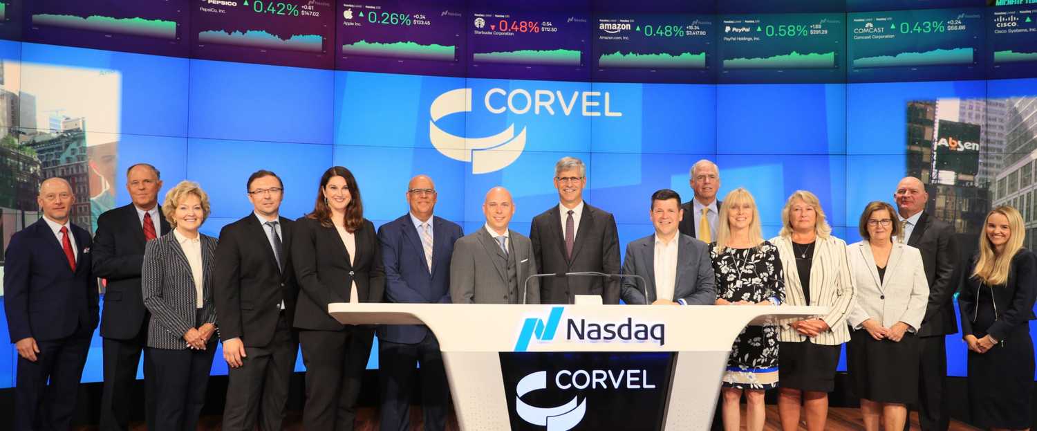 CorVel employees standing behind the Nasdaq podium
