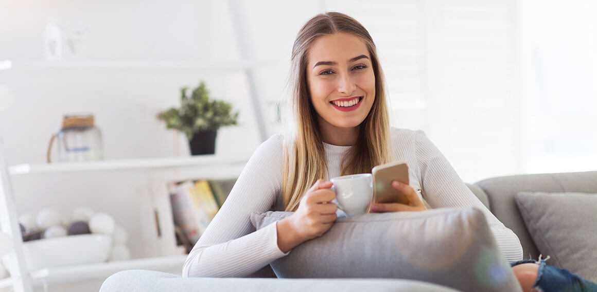 Woman on the couch drinking some tea as she engages in her recovery with the Peerwell app