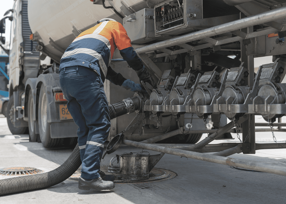 A tanker truck driver delivers gasoline to a gas station