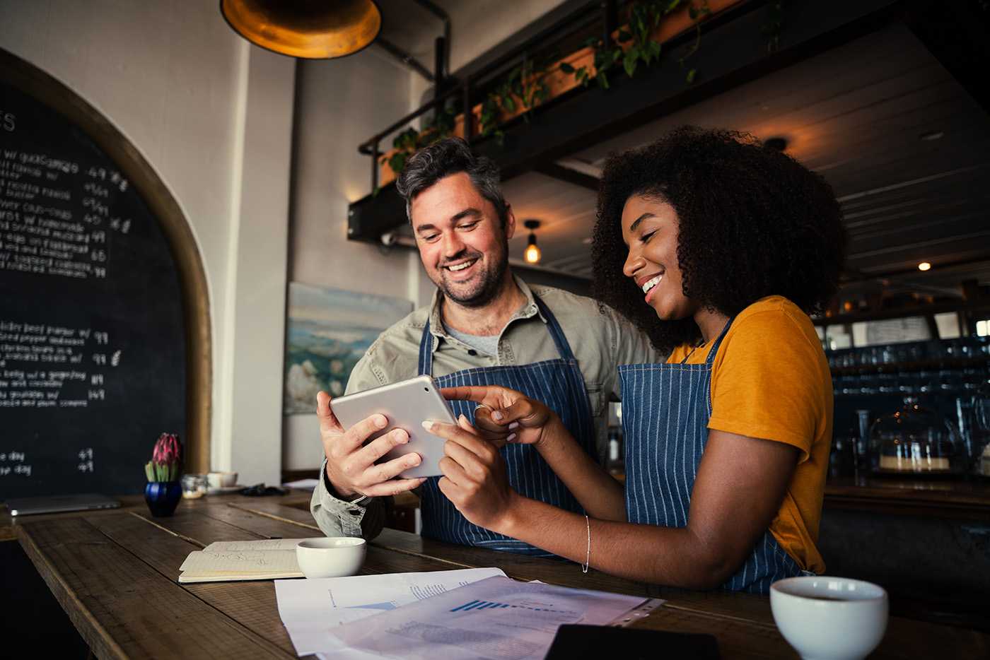 two happy baristas at work on a tablet speaking with a corvel nurse