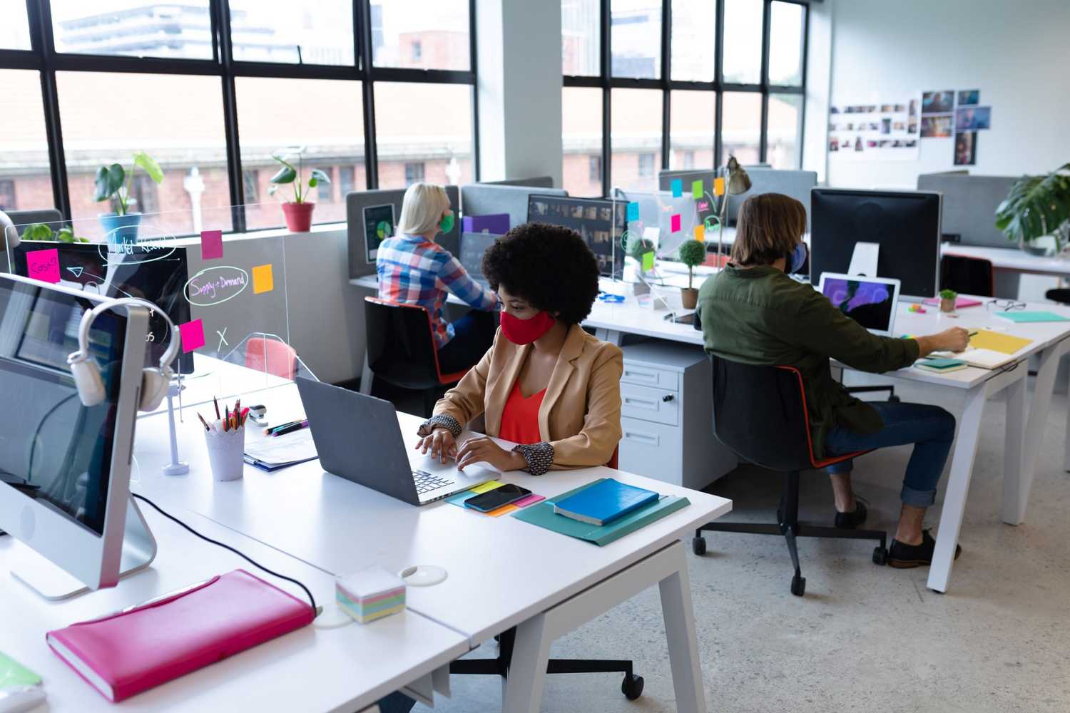 Three colleagues working at their desks with masks on