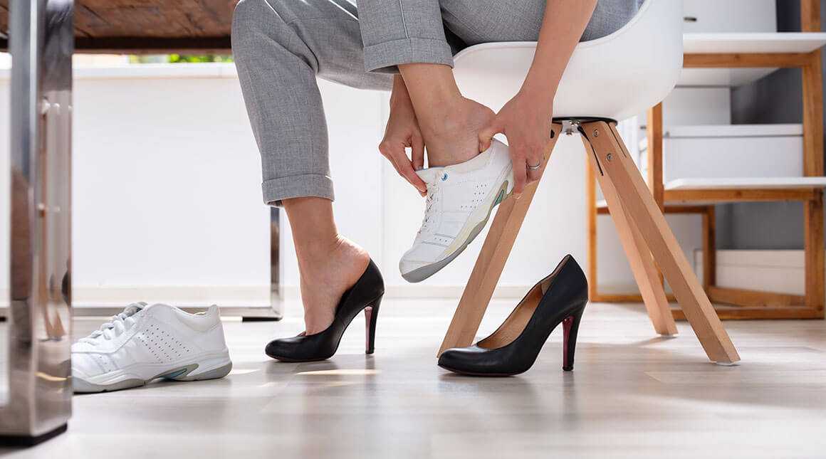 A woman switching out of her heels into tennis shoes to exercise at work