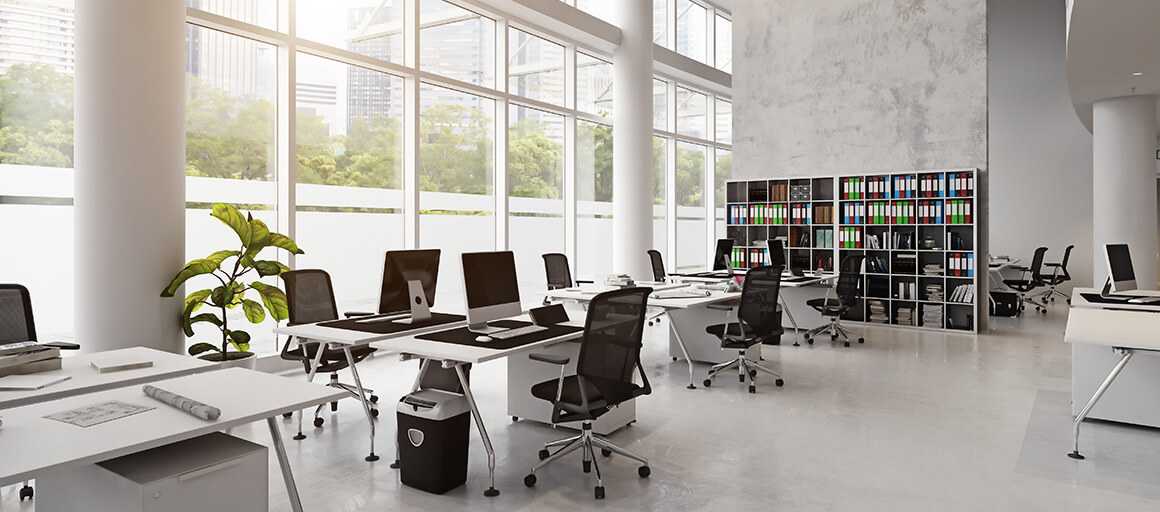 An empty office with desks, computers, and a cabinet full of binders