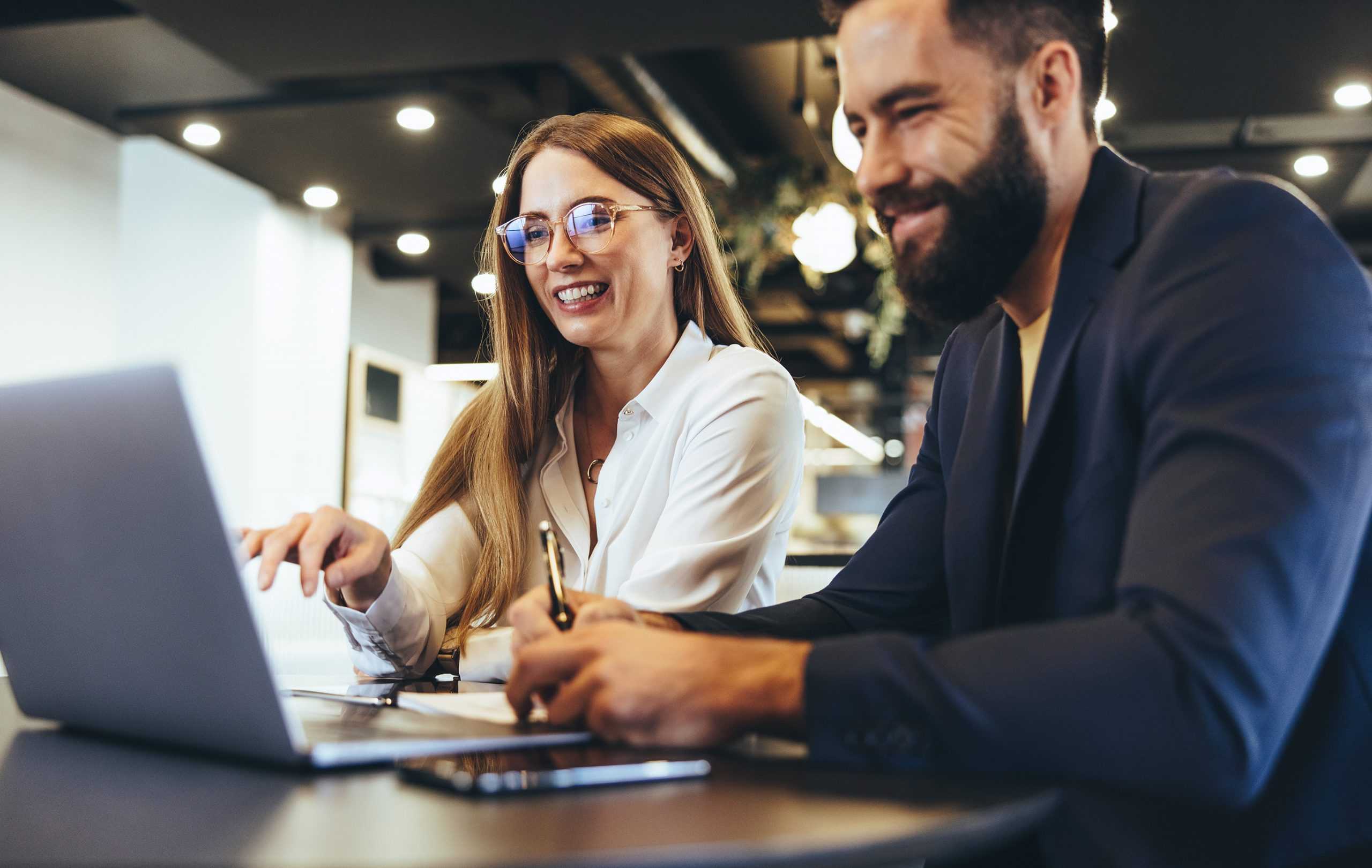 two happy business professionals on a laptop learning about corvel workers comp technology