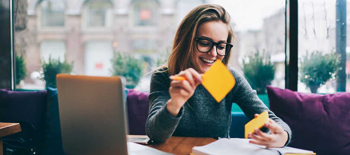 A woman smiling, using sticky notes to organize her meditative thoughts