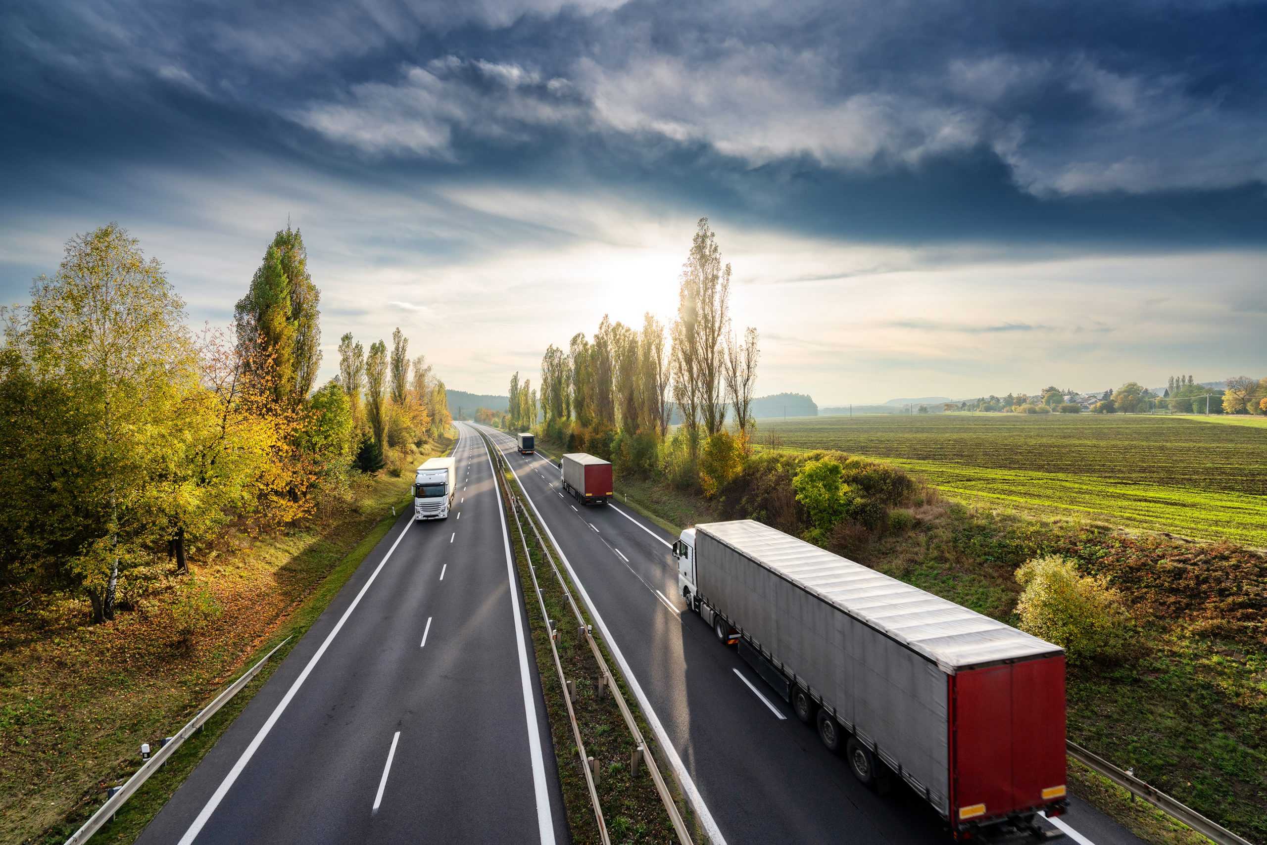 four semi-trucks covered by corvel's auto liability management driving on a highway