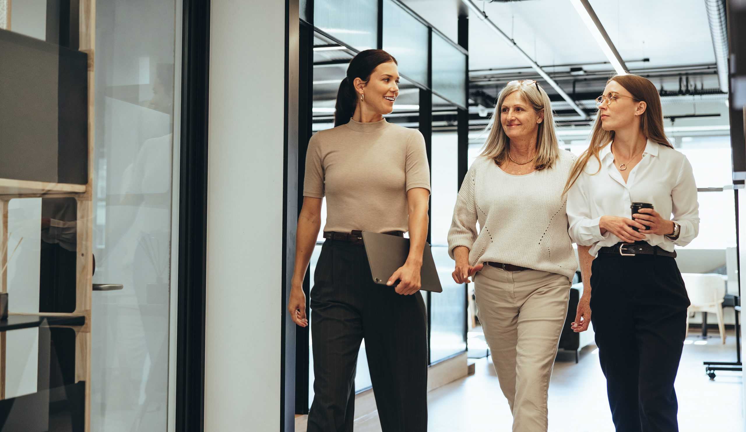 three businesswomen walking down hallway discussing corvel's workers comp medicare services