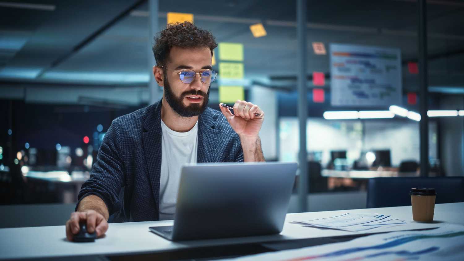 Young professional Risk Management Director Working on Laptop Computer in Big City Office Late in the Evening. Businessman Preparing for a Marketing Plan in Conference Room.
