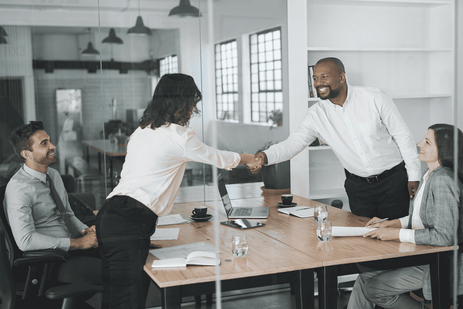 Smiling businesspeople standing in a boardroom shaking hands together