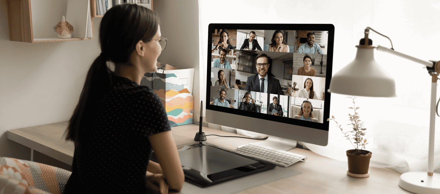 A woman on her computer in a virtual meeting with multiple colleagues