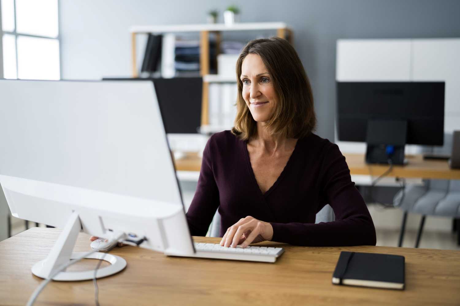 A woman smiling and reading on her computer