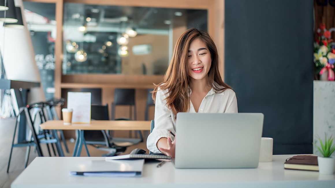 A woman smiling while working on her computer