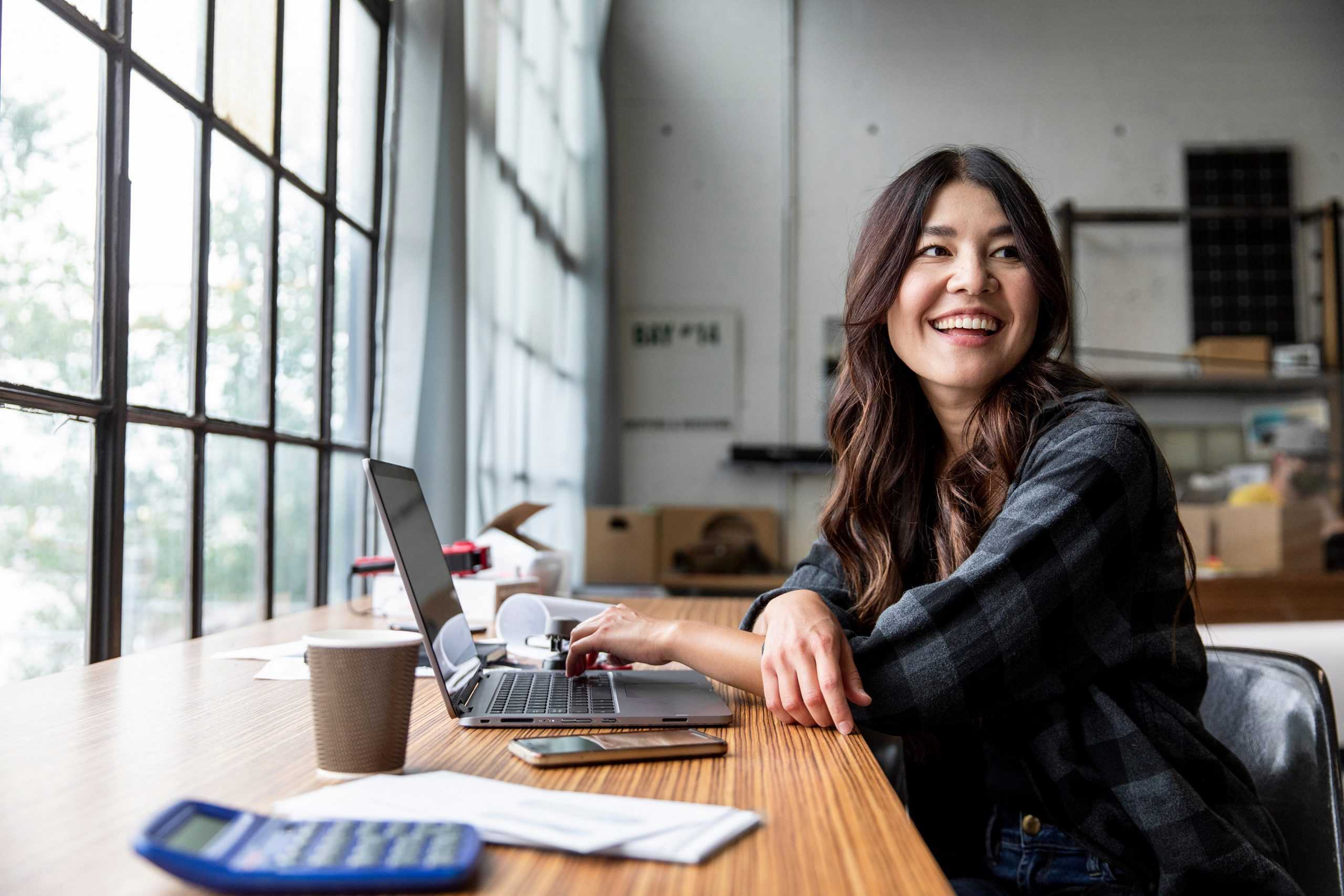 young woman on her computer smiling and reading corvel workers comp insights