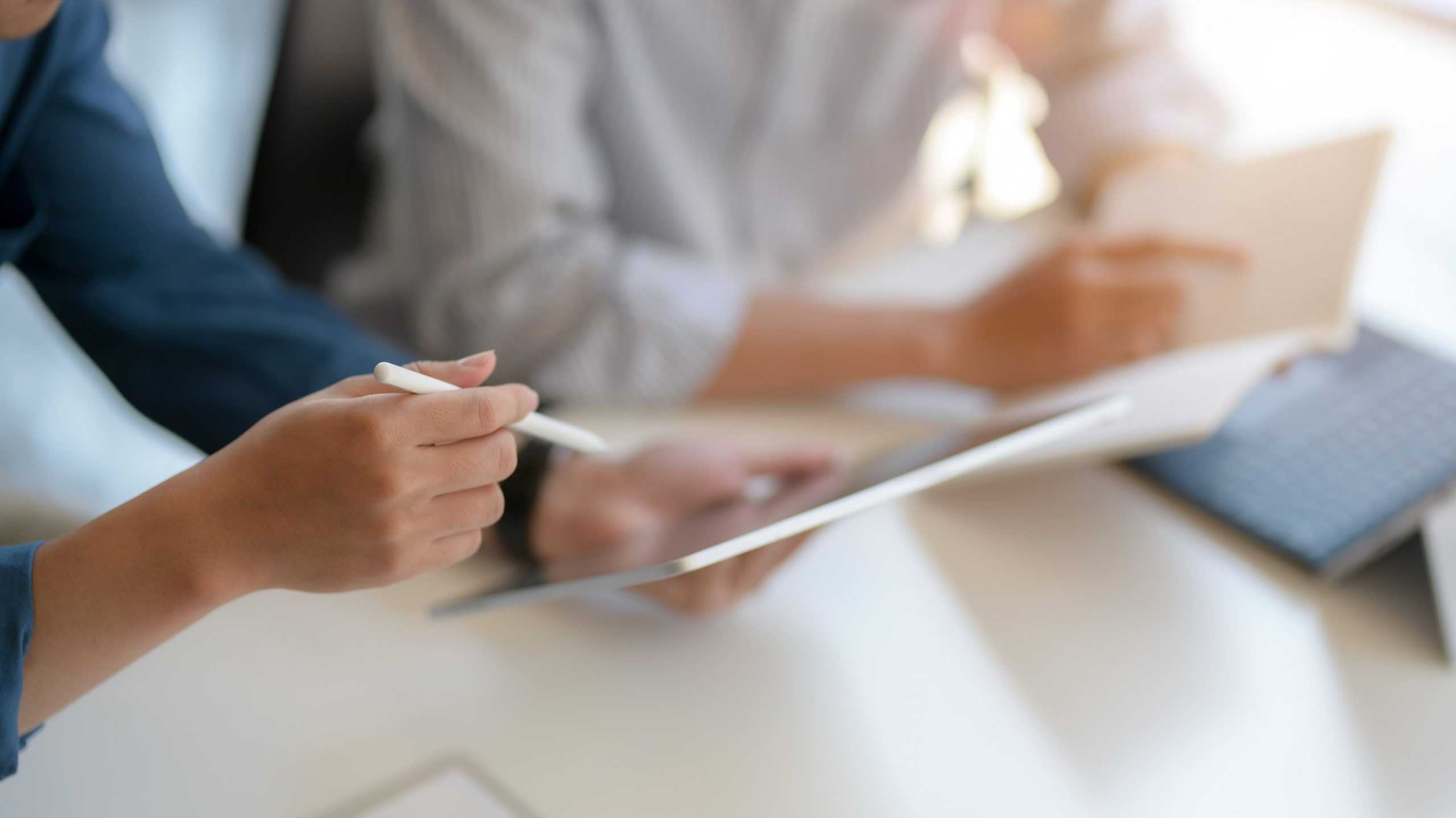 a cropped view of two business professionals reviewing legal nurse files on a tablet and paper