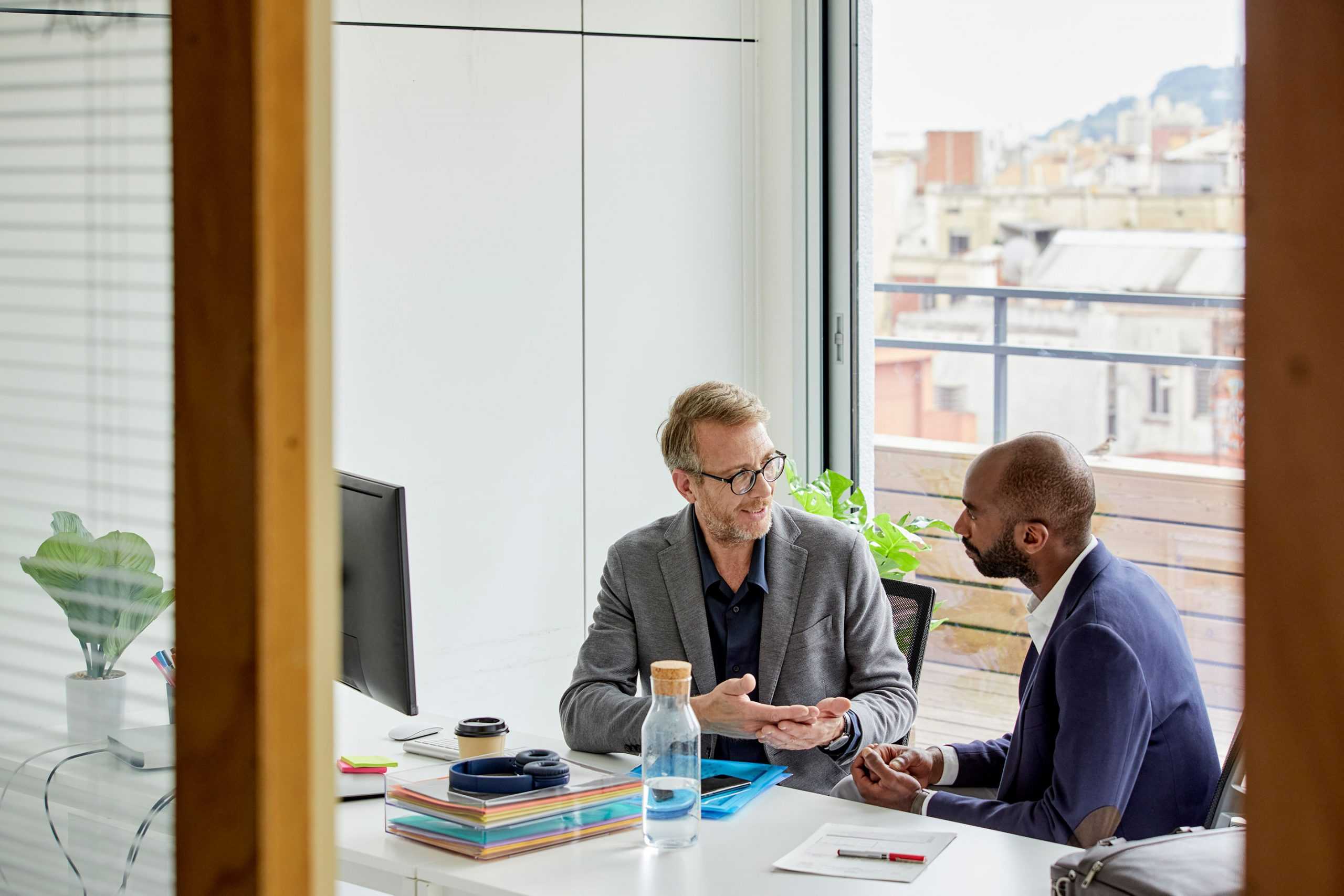 two business men sitting at a desk having a discussion on CorVel company