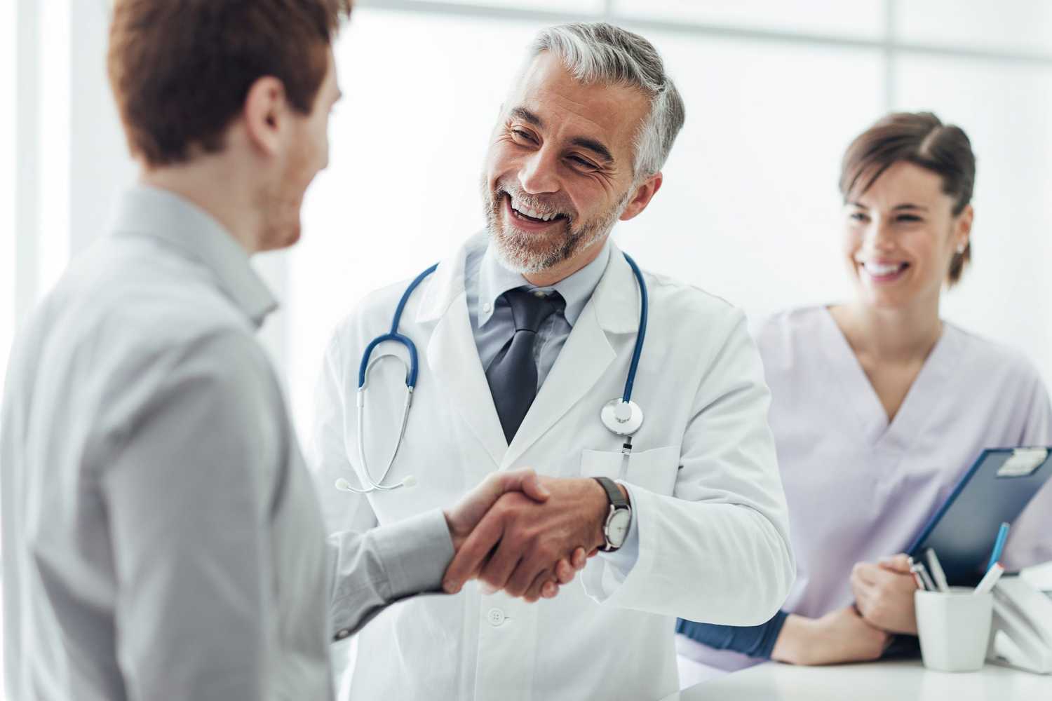 smiling male doctor in CorVel's provider network shaking hands with male patient