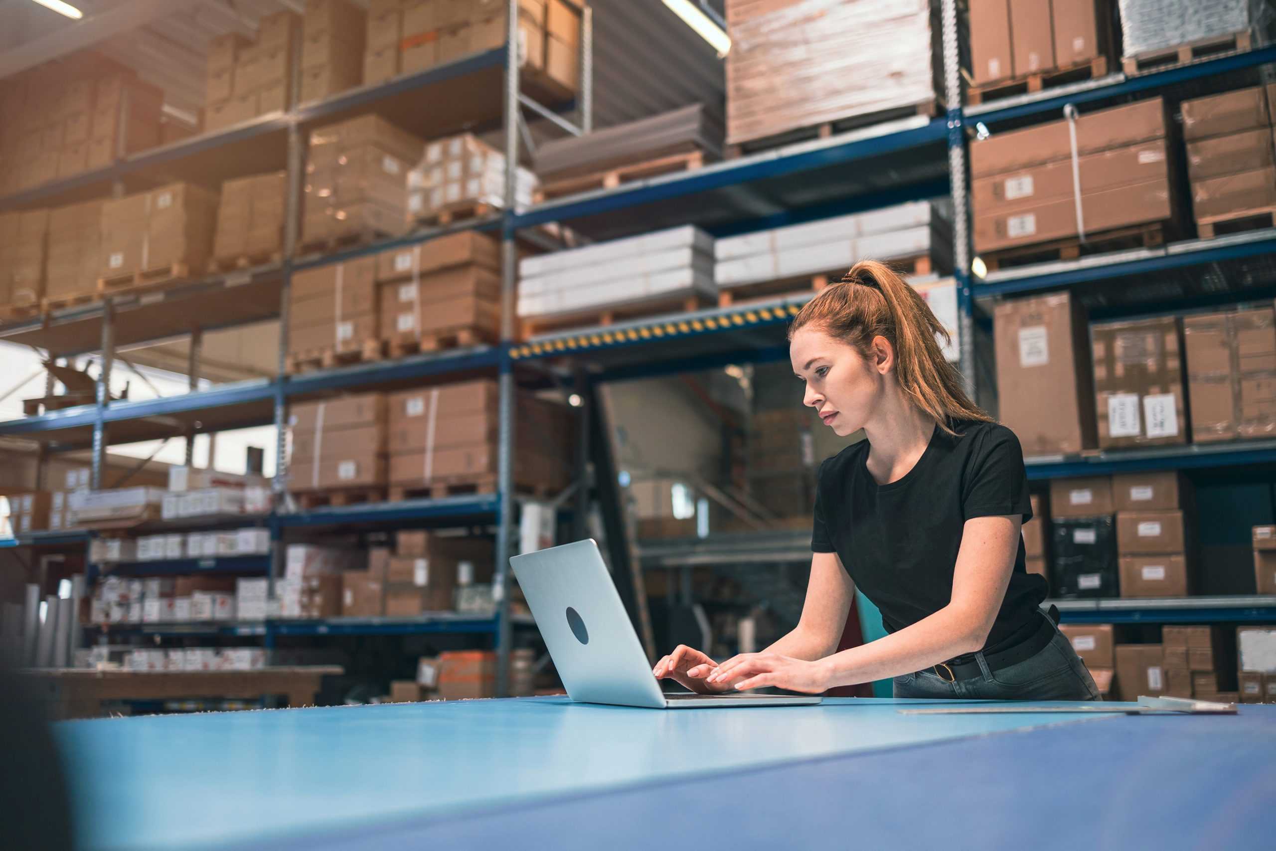 a female worker in a warehouse on her laptop collaborating with a corvel return to work coordinator