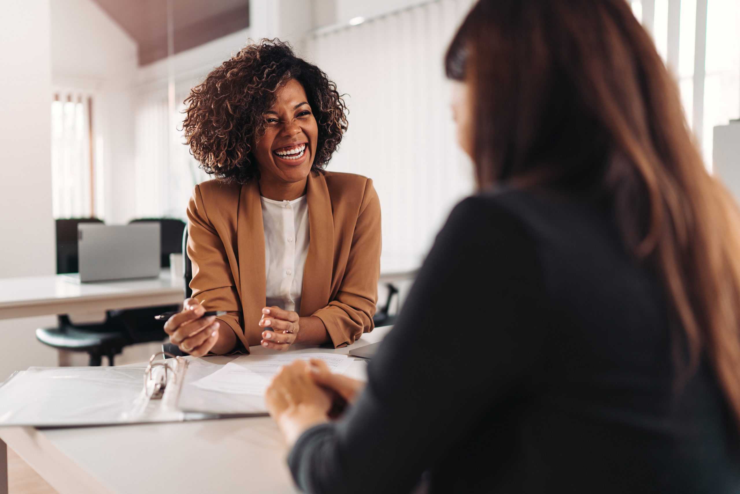 two happy businesswoman sitting together discussing CorVel's CogencyIQ services