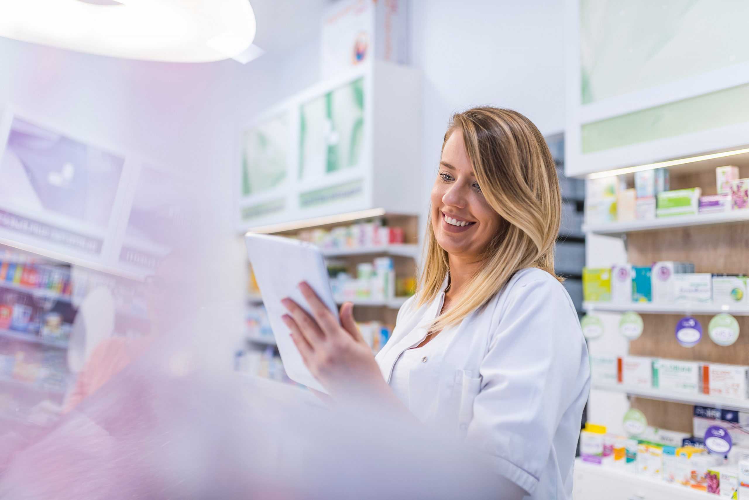 a happy female pharmacist using corvel's workers comp pharmacy benefit management on a tablet