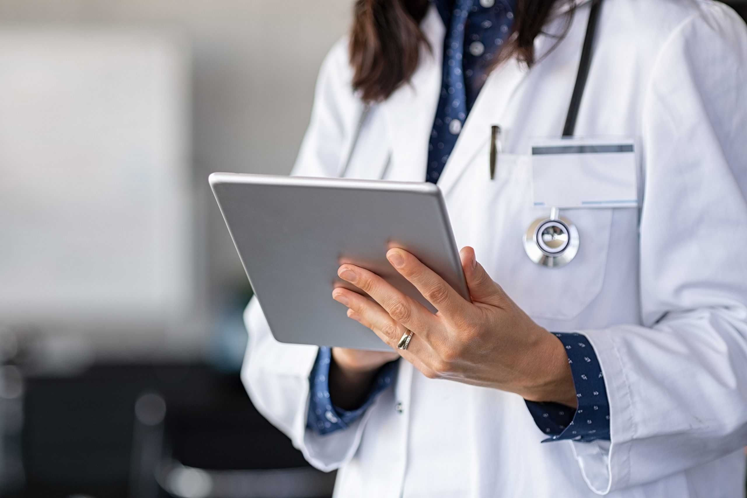 a female doctor working on a tablet using corvel's utilization review management