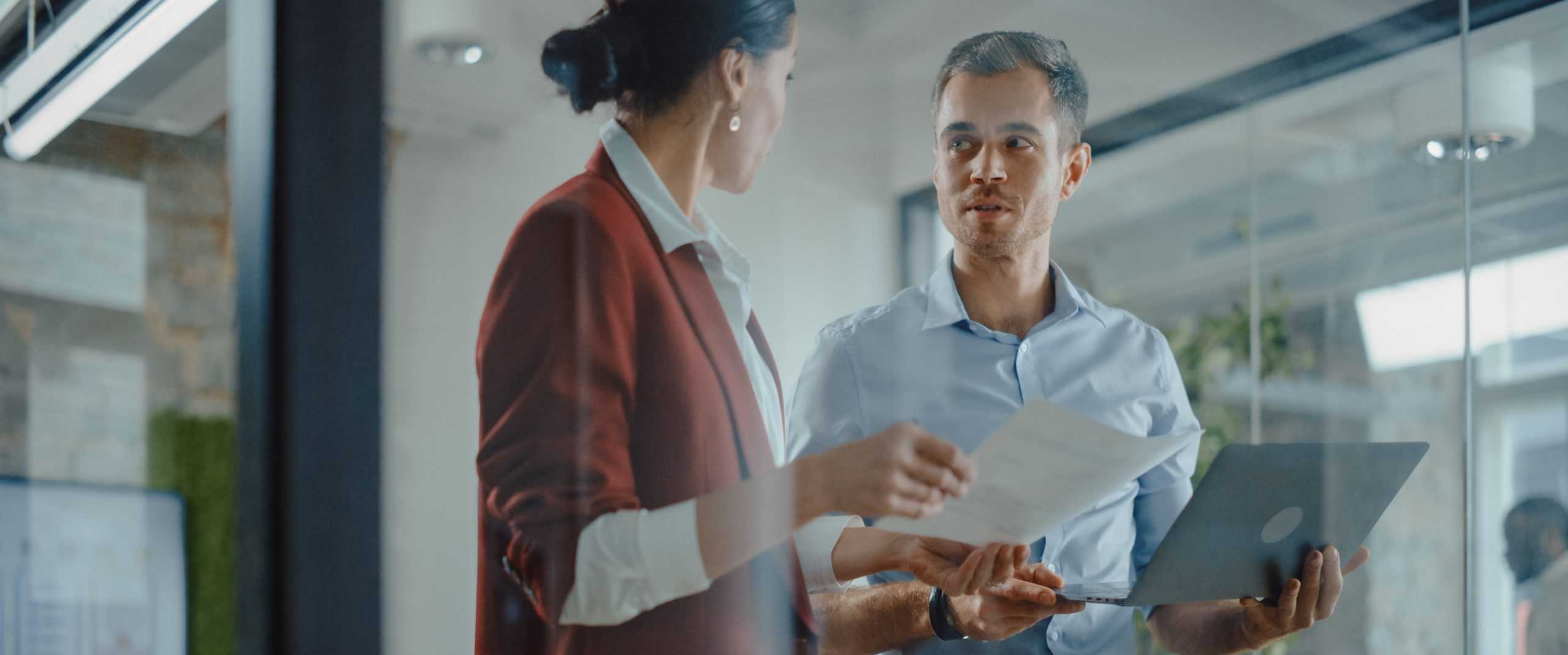 businessman and businesswoman standing together reviewing workers comp disability management services