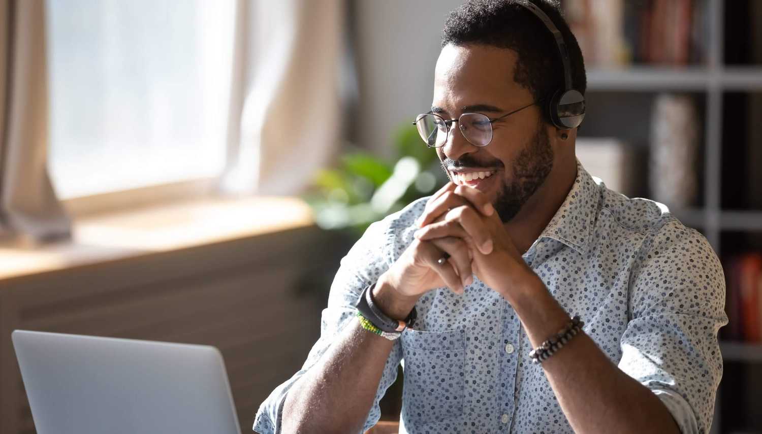 A man with a headset on, smiling while looking at a computer