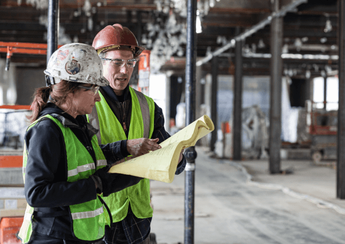 male and female construction workers standing reviewing workplans
