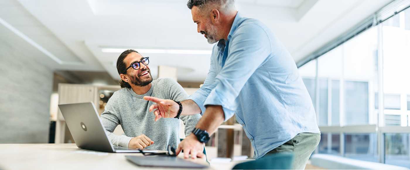 two happy businessmen working together on a computer reviewing corvel's bill reivew services