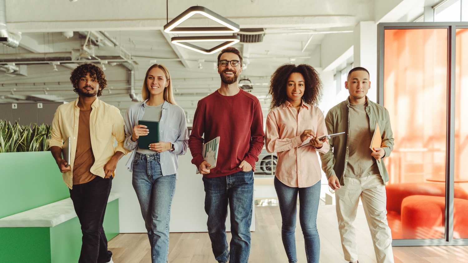 A diverse group of young professionals walk confidently through a modern office, reflecting CorVel’s commitment to innovation, tech-driven growth, and future insurance leaders.